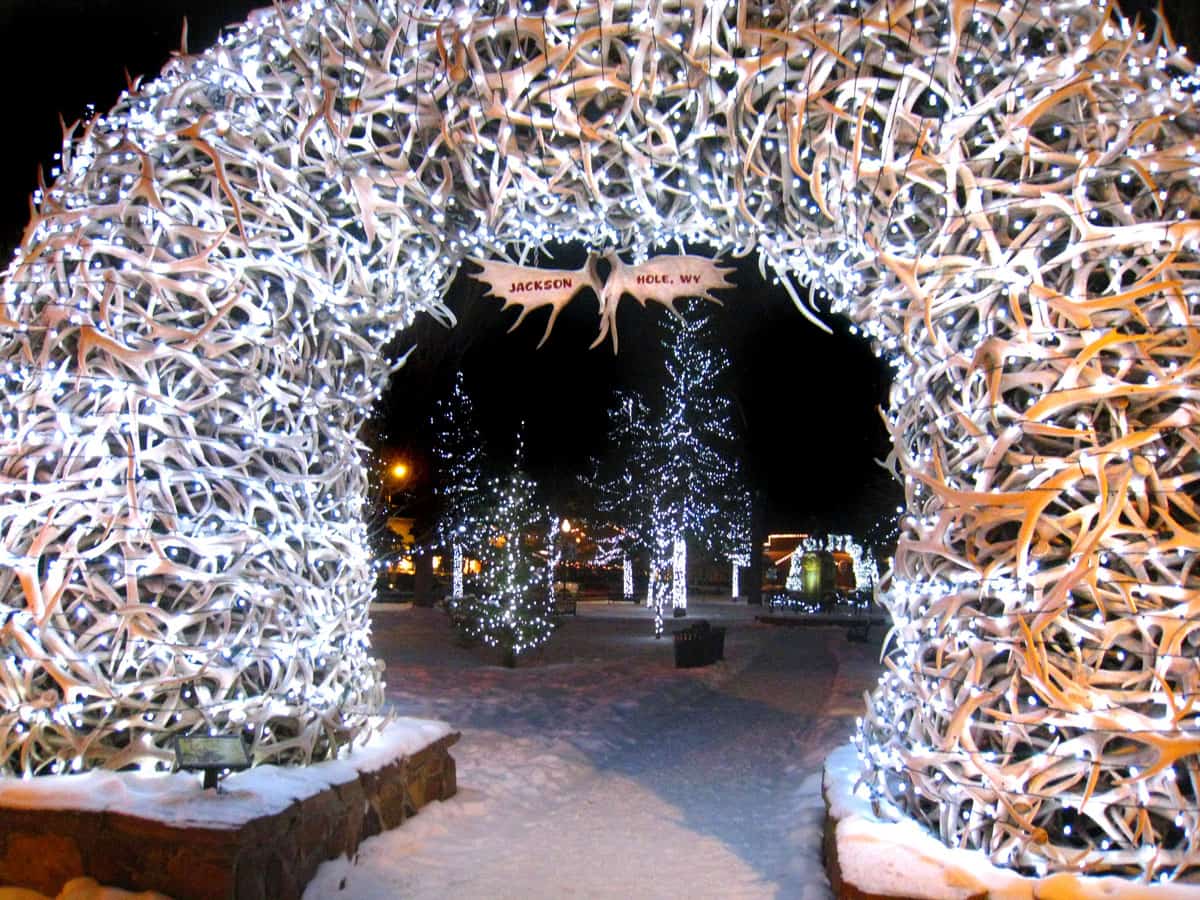 The antler arches in Jackson Wyoming lit with Christmas lights, glowing in the snow at night. 