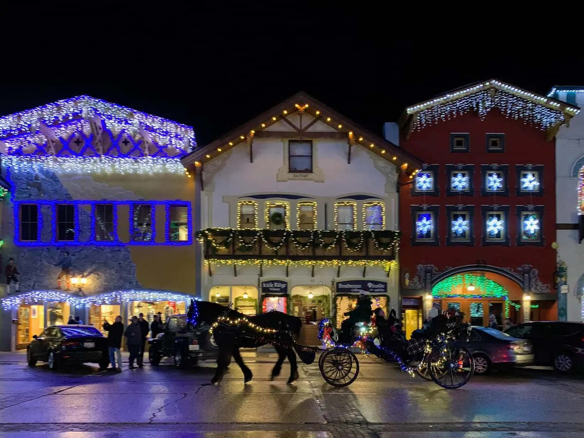A horse and cart decorated in lights takes people past buildings with Christmas lights in the town of Leavenworth. 