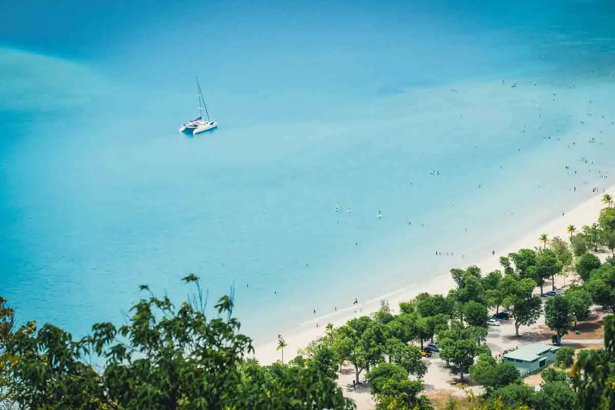 A yacht anchored in clear blue water off a white sand, palm fringed beach in the US Virgin Islands. 