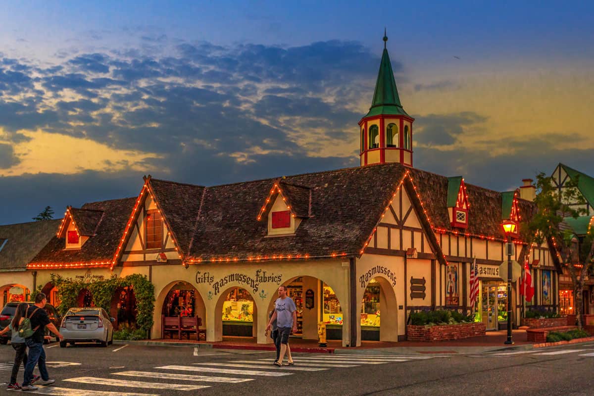 A man crosses at the zebra crossing in front of a danish style building decorated in lights in the small town of Solvang in the US.
