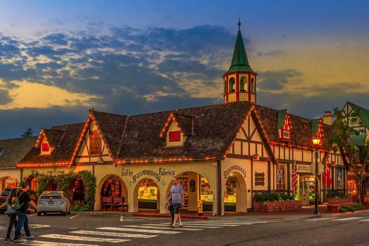 A man crosses at the zebra crossing in front of a danish style building decorated in lights in the small town of Solvang in the US.