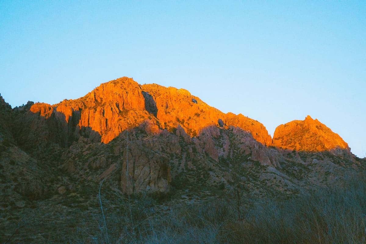 Sunsetting over a red rock mountain with blue sky. 