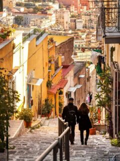 Young couple walking down hill on a narrow street overlooking the city of Naples in Italy.