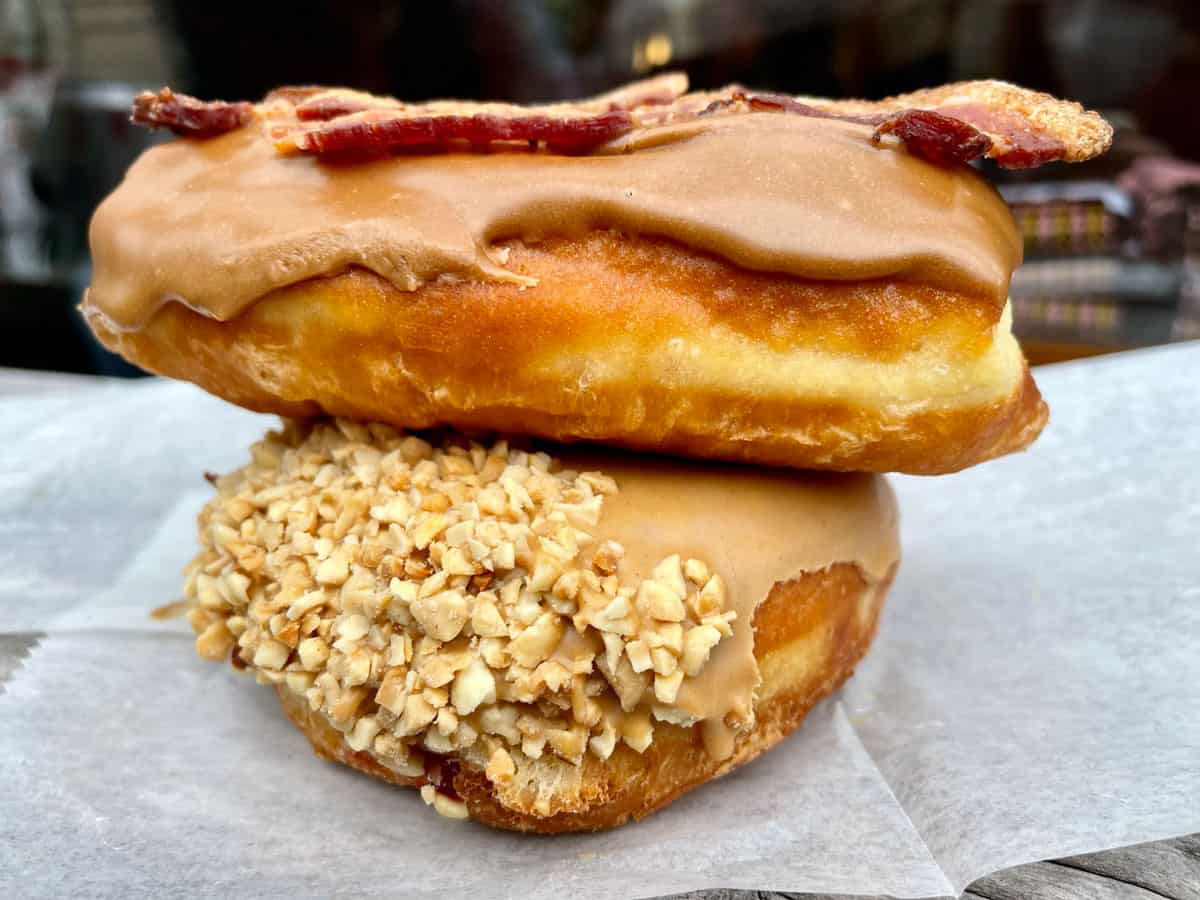 Two donughts stacked with caramel frosting and maple bacon on top. 