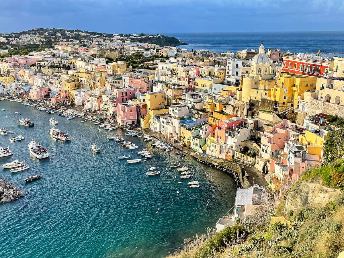 The blue bays of Procida Island doted with fishing boats, Colourful buildings cover the narrow centre of the island. 
