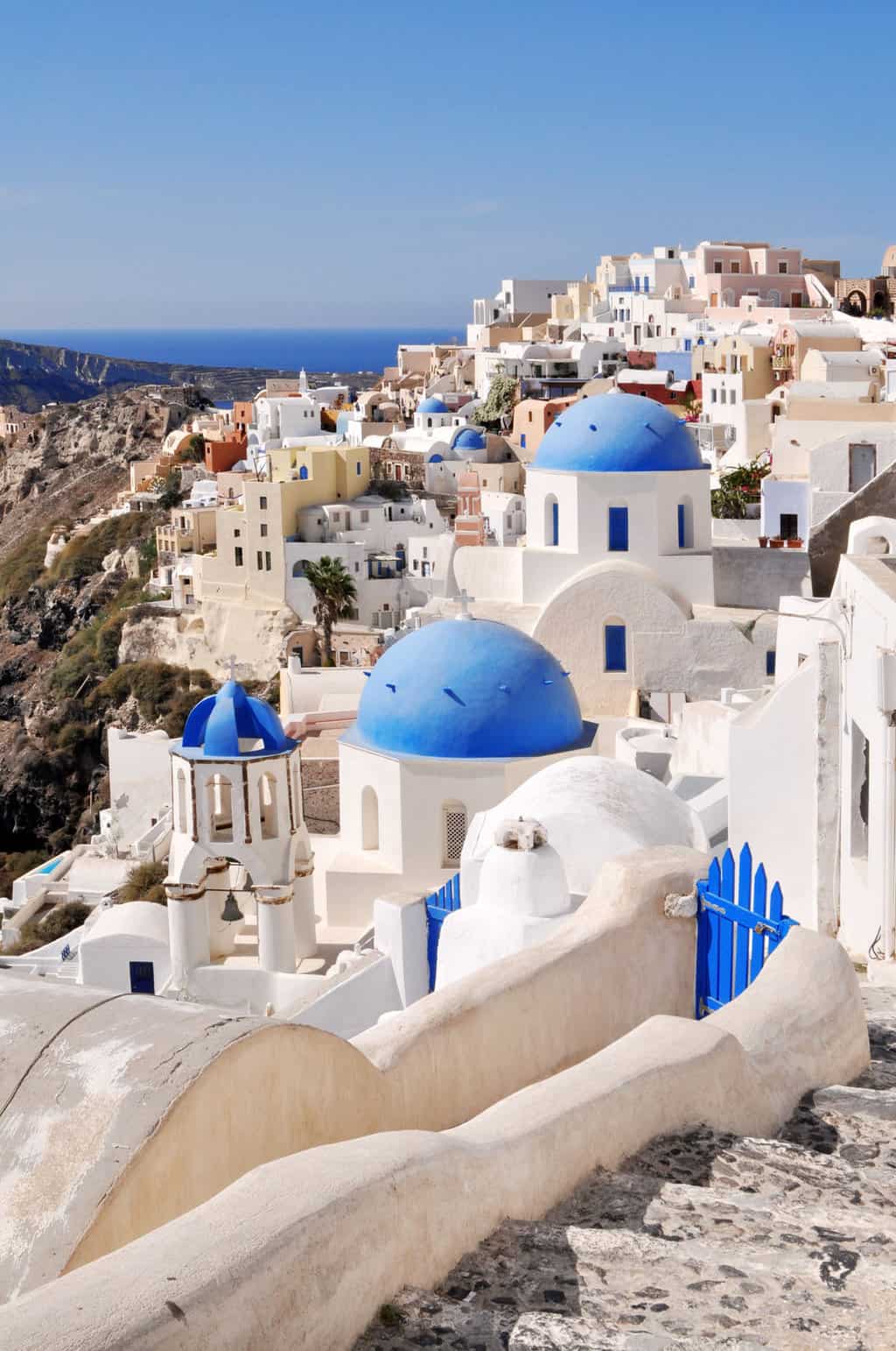 White buildings trace the top of the island in Santorini with the typical blue domed churches. 