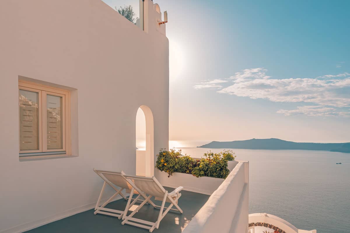Typical white terraced house with two chairs over looking the ocean in Santorini Greece.