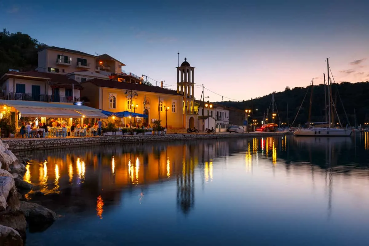The lights from waterfront restaurants reflect in the water at dusk on the island of Meganisi Greece.