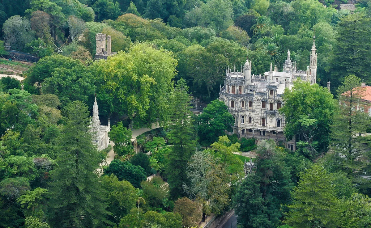 Aerial view of the castle Quinta da Regaleira surrounded by lush green woodland in Sintra.