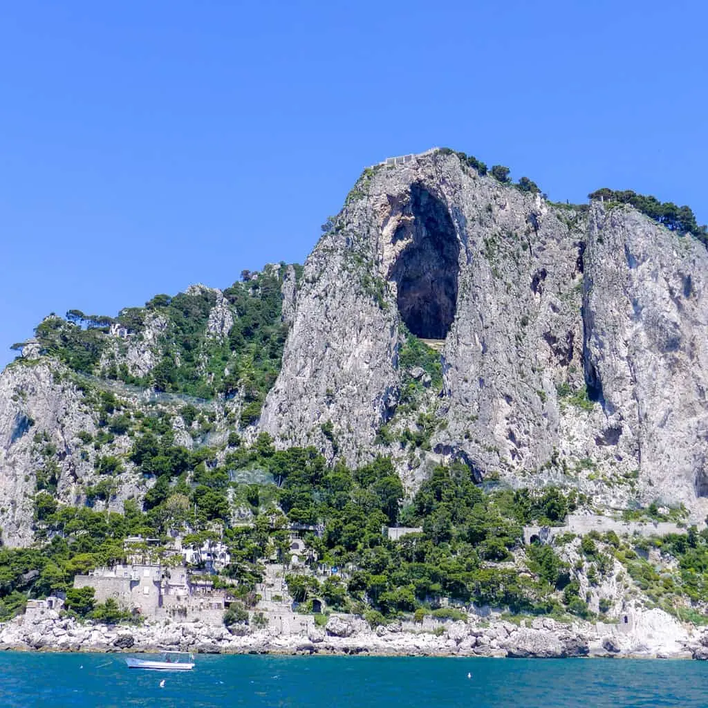 Boats moored on blue waterin front of cliffs on Capri Island.