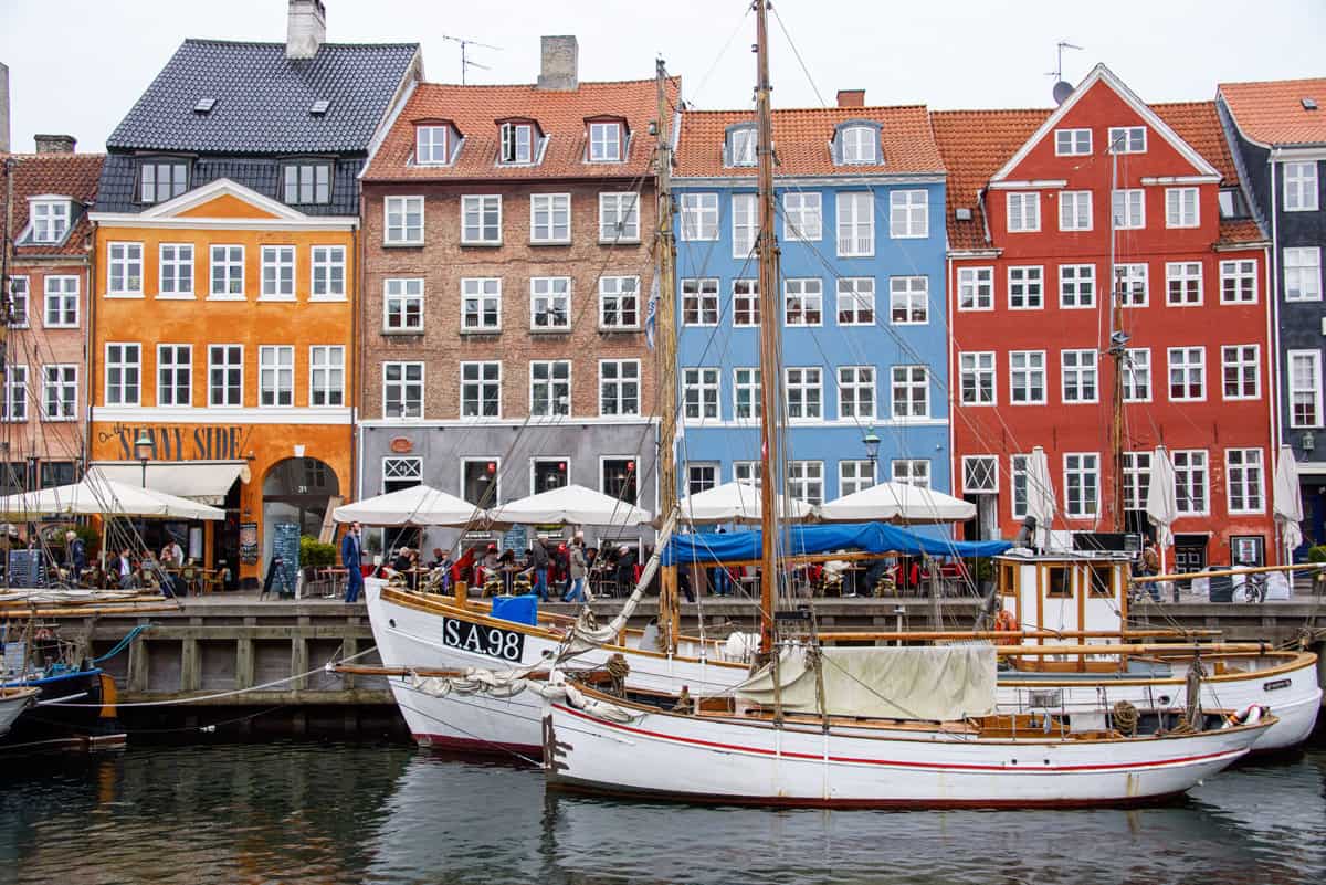 Wooden sailing boats moored infront of the coulful houses in Copenhagen in Denmark. 