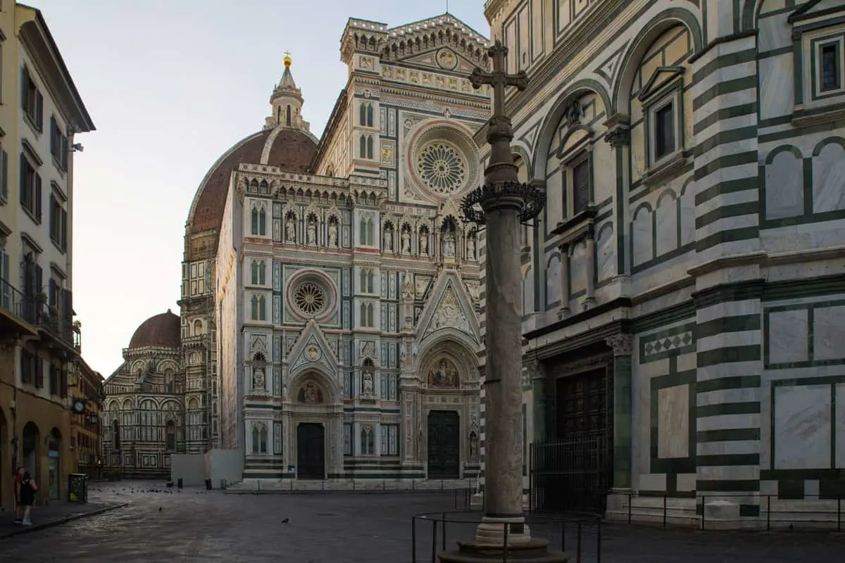 Looking down the Piazza Duomo in Florence, past the green and white marble baptistry to the cathedral of Florence.  The streets are empty as it is early morning. 