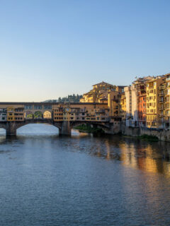 The Arno River in Florence at sunrise with the famous Ponte Vechio Bridge in the distance.