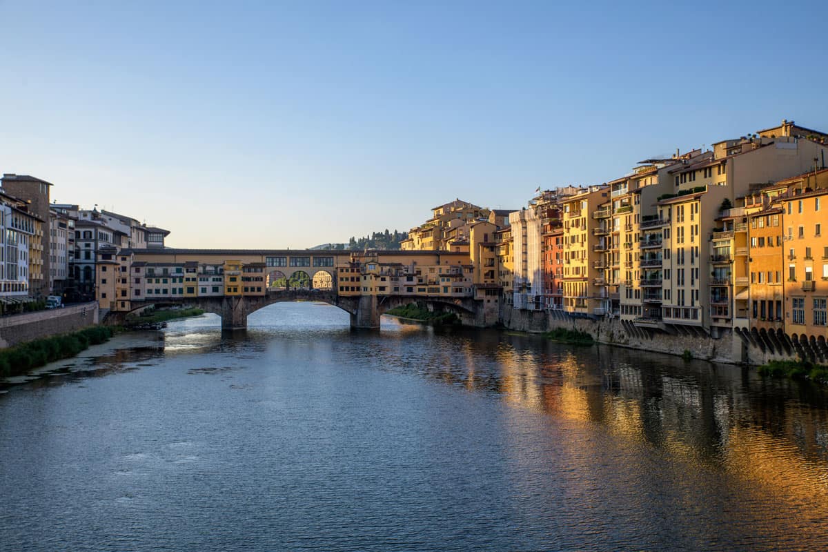 The Arno River in Florence at sunrise with the famous Ponte Vechio Bridge in the distance. 