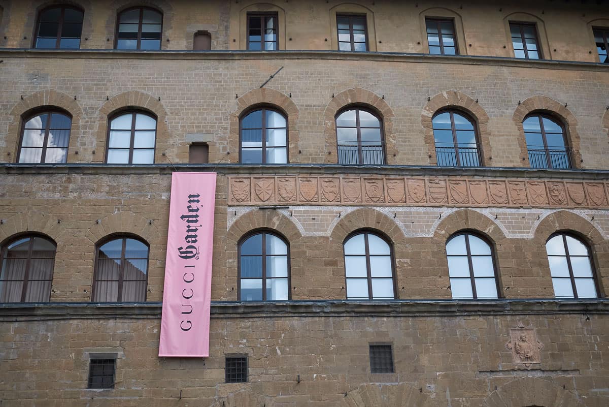 Historc brick building in Florence with a pink banner saying Gucci Garden. 
