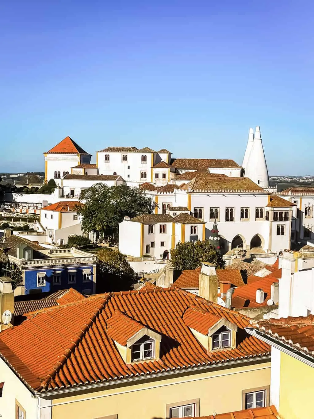 Views over the red roof tops in Sintra Portugal towards the National palace of Sintra with the striking white cone towers. 