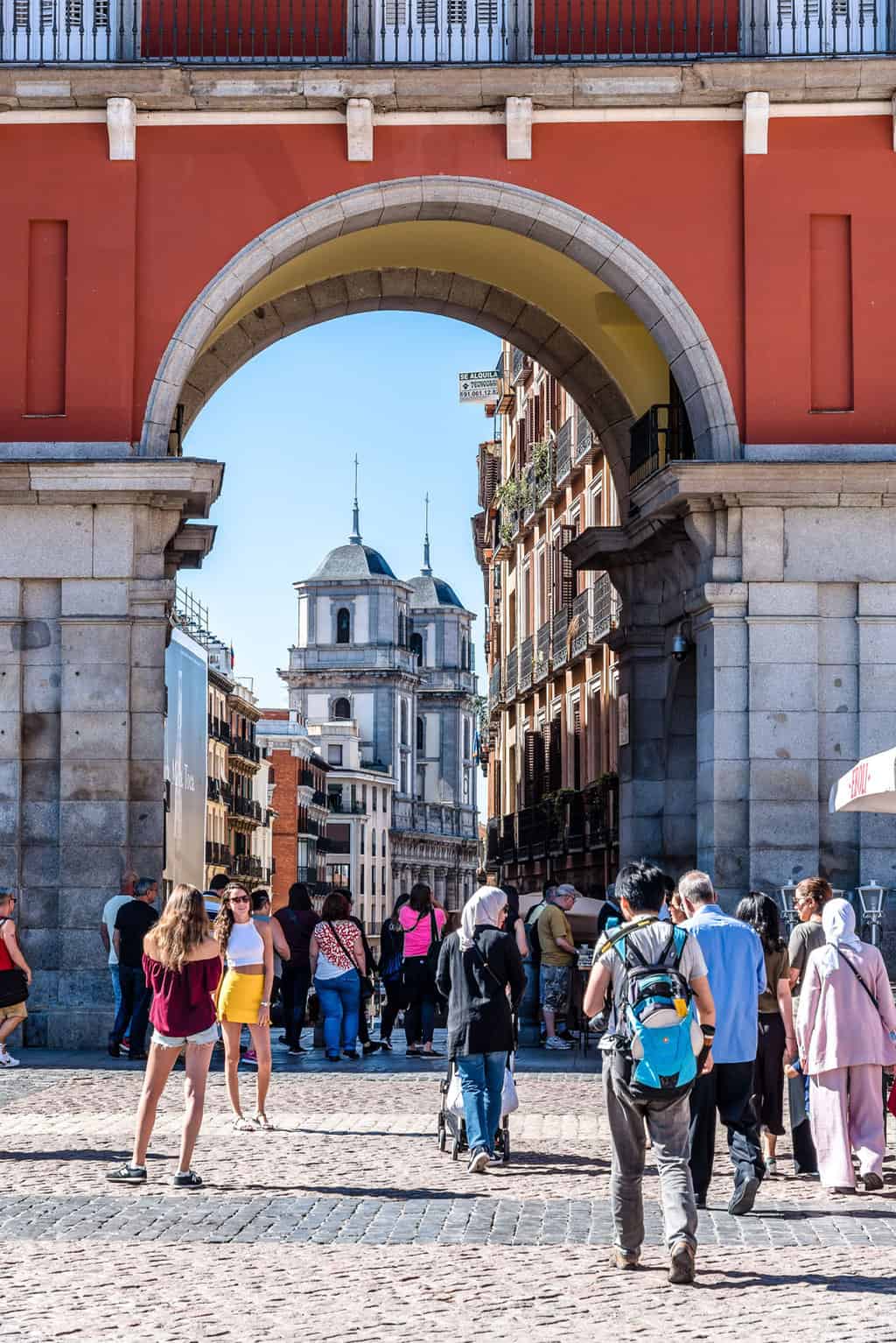 Tourists standing in front of an archway leading to the historic centre in Madrid. 