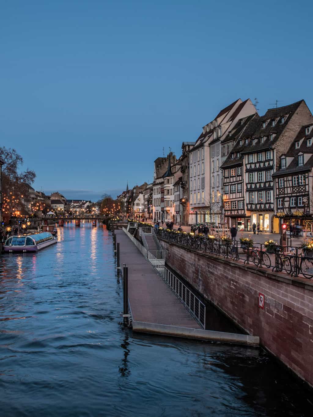 Twinkling lights decorate the river edge in the old town of Strasbourg at Christmas.