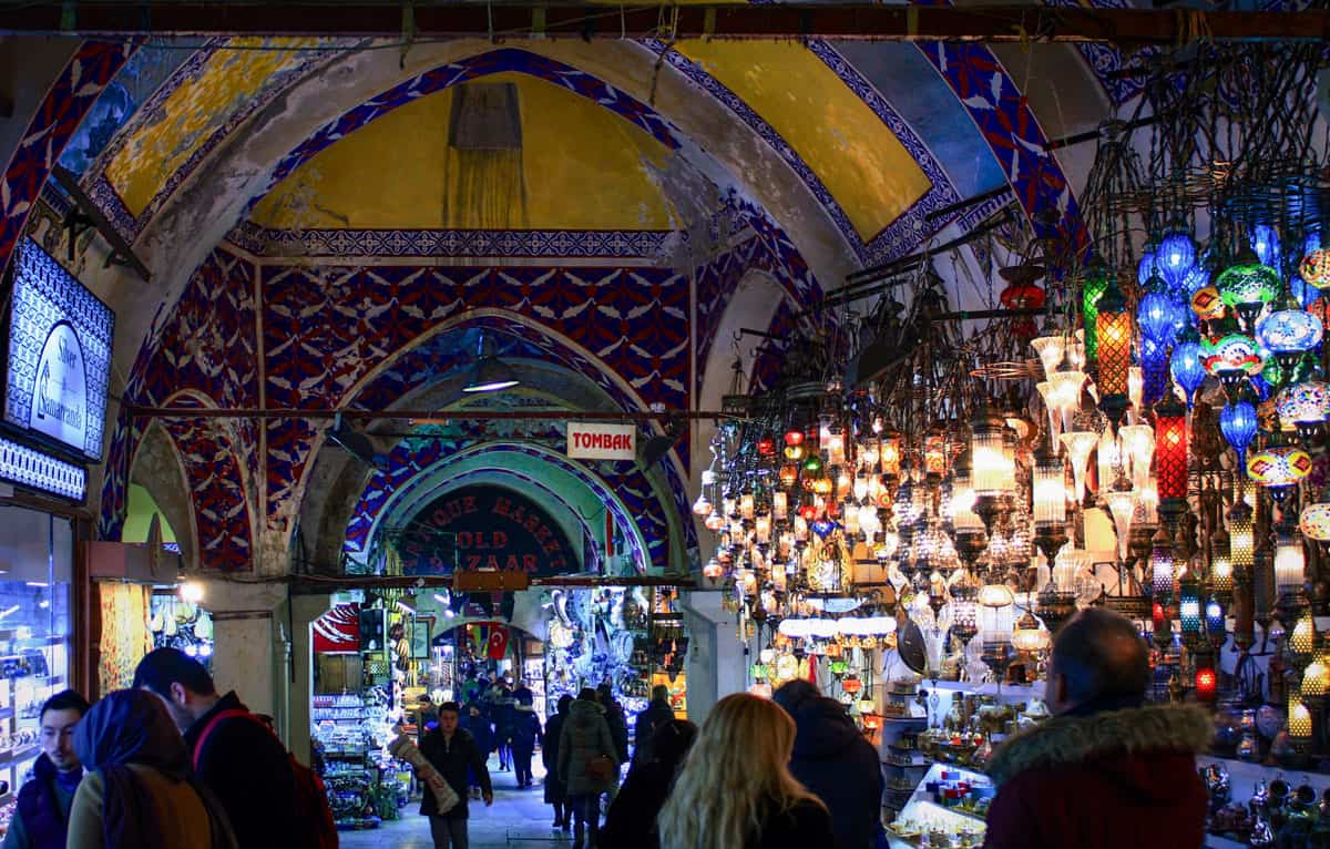 Colourful lanterns hang in the ancient streets of the Grand Bazaar of Istanbul, the oldest and largest covered market in the world. The walls are painted in bright colours and patterns that show the age of time. 