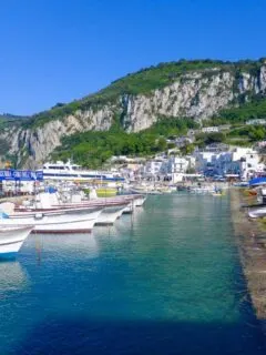 Colourful fishing boats in neat rows on the banks of a harbour on Capri Island.