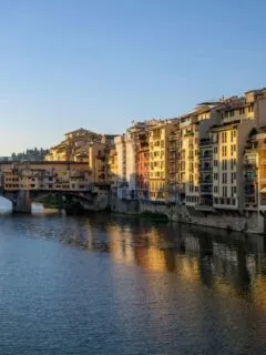 The Arno River in Florence at sunrise with the famous Ponte Vechio Bridge in the distance.