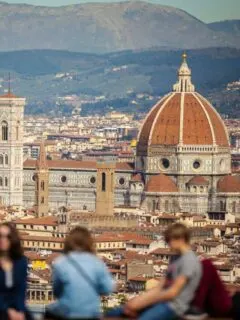 Tourists admiring the view over Florence from Piazzale Michelangelo. The city scape is in focus and the tourists are out of focus.