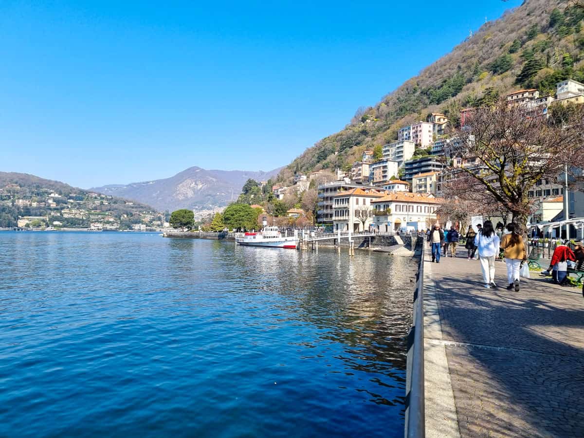 People strolling along the lake side in the pretty town of Como on a sunny day.