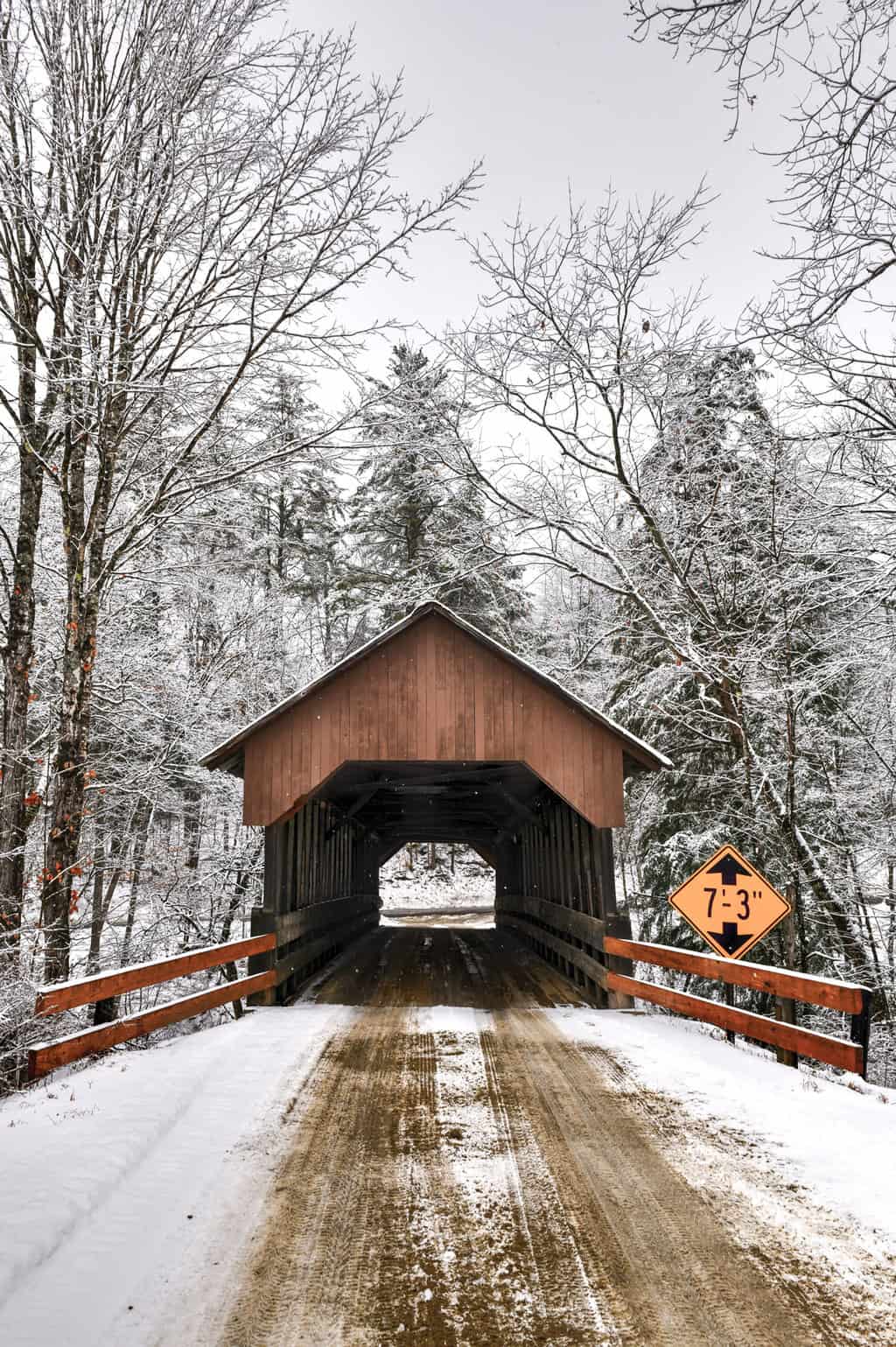 Wooden covered bridge in a snowy landscape in New Hampshire.