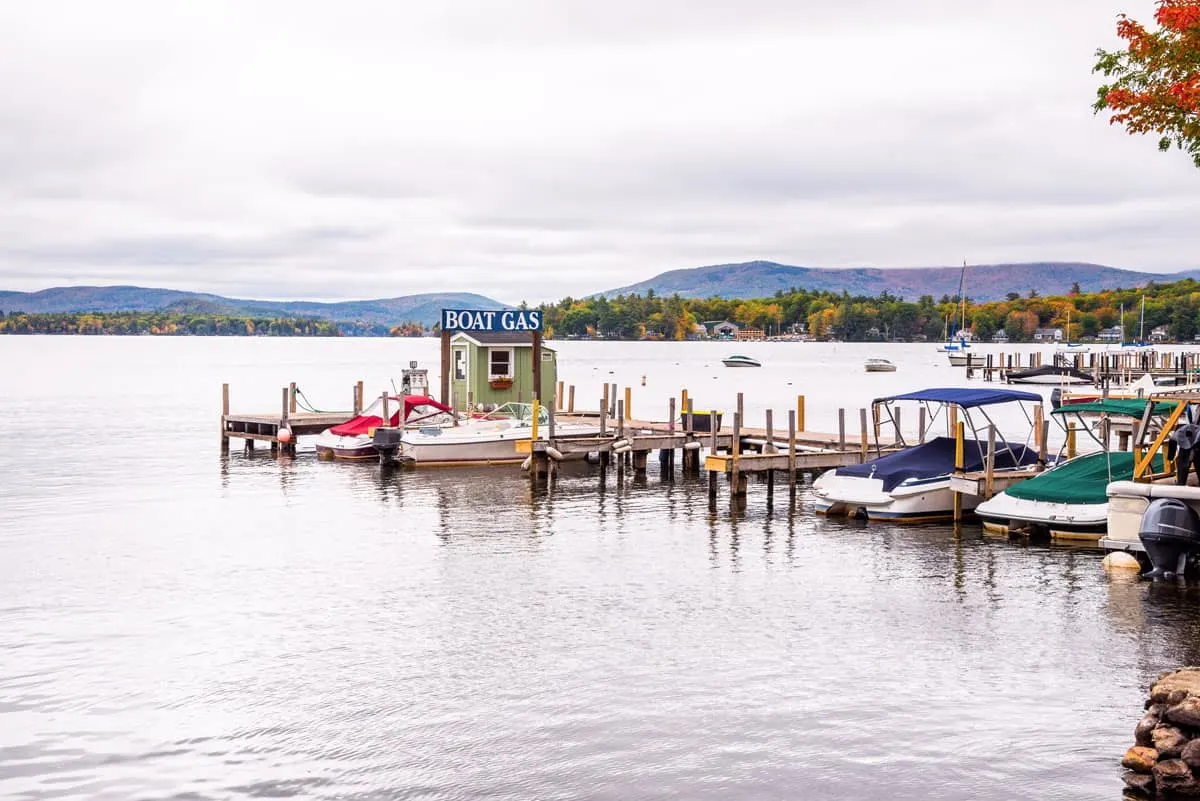 Boats parked at a lake jetty with a small wooden gas station at the end. The white sky suggests winter on the lake.