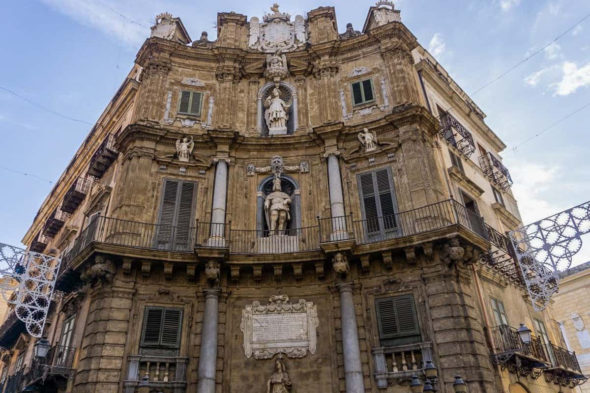 A curved historical building in Palermo decorated with columns and statues in the Italian style.