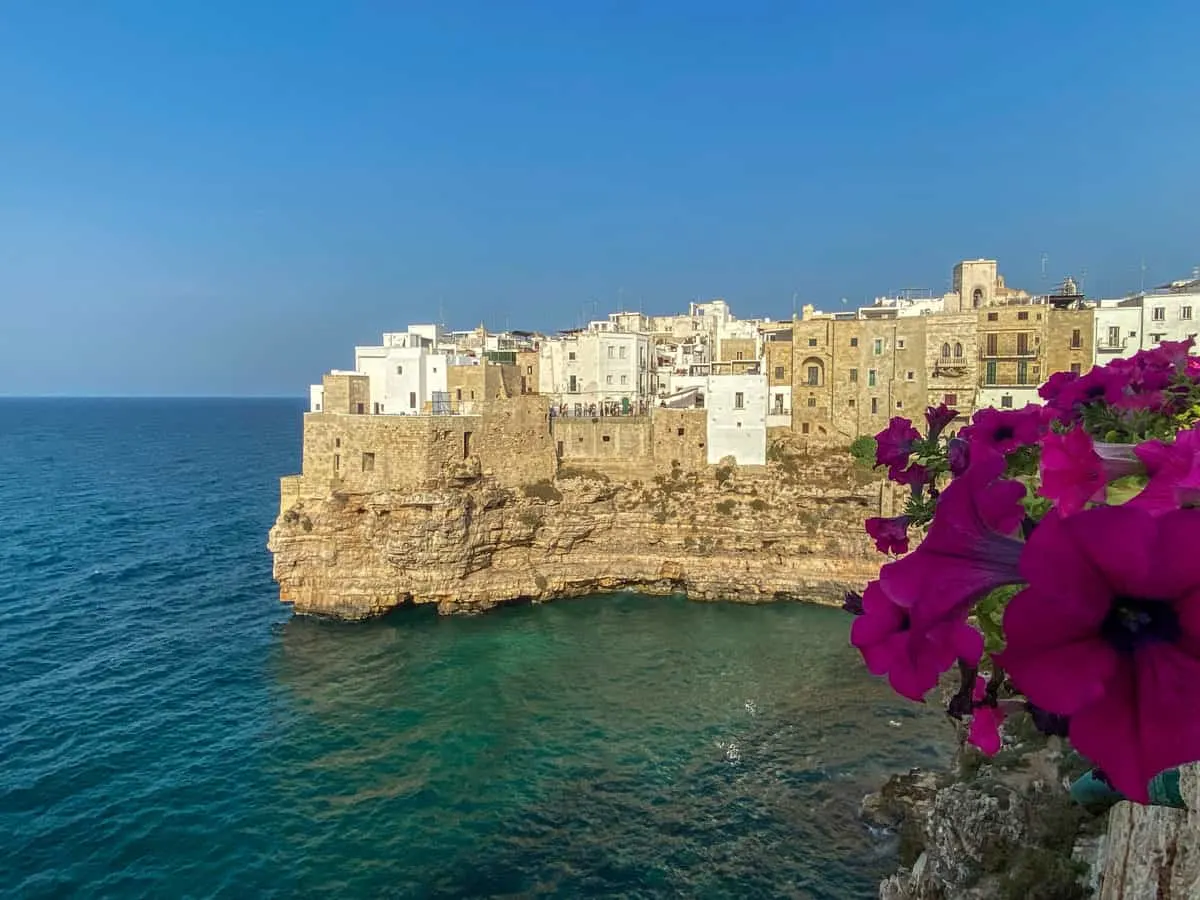 A white washed Italian village on top of sand coloured cliffs overlooking the ocean. 