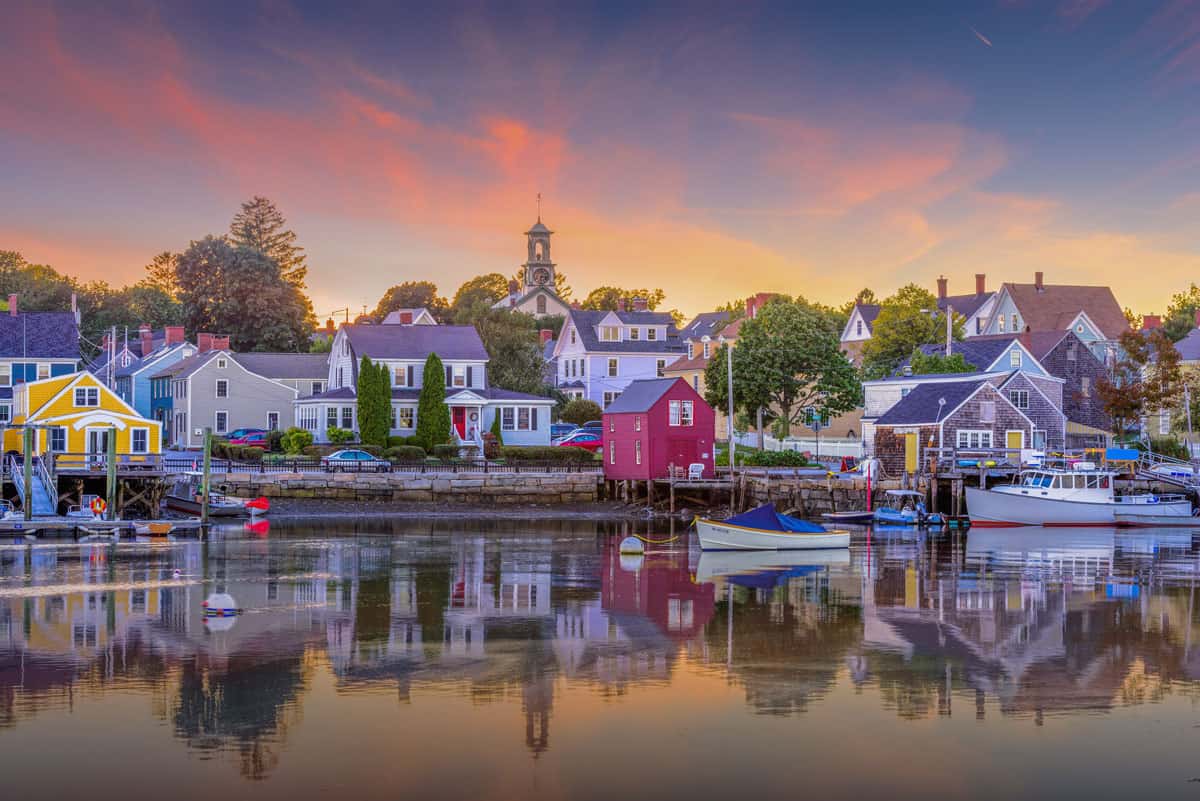 Sunset casts a soft pink and orange glow and reflections in the water in the colourful fishing village of Portsmouth.