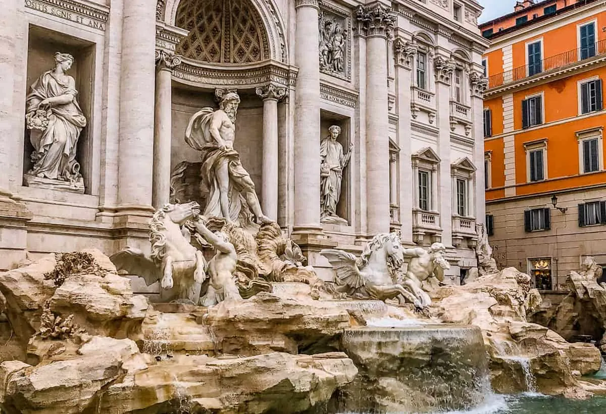 The Trevi Fountain with an orange building in the background. 
