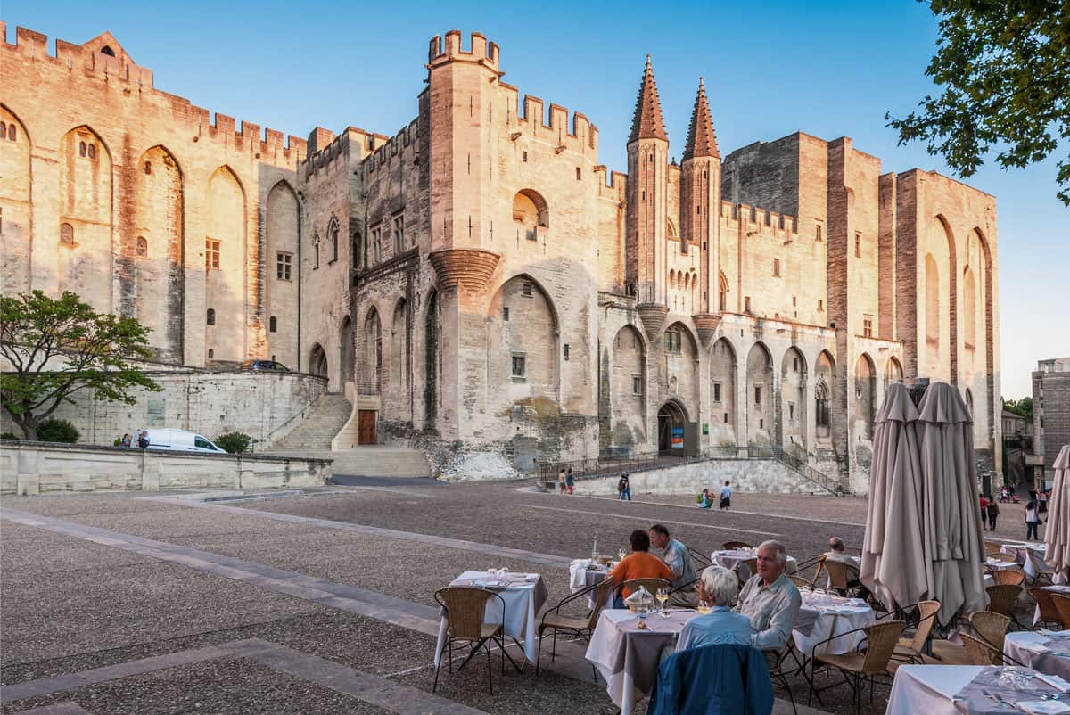 Pope palace in Avignon. Central square with people eating lunch in front of the palace in the cafe.