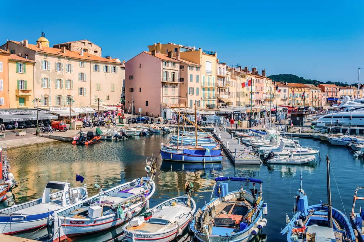 Colourful buildings and brightly painted fishing boats in the harbour of St Tropez.