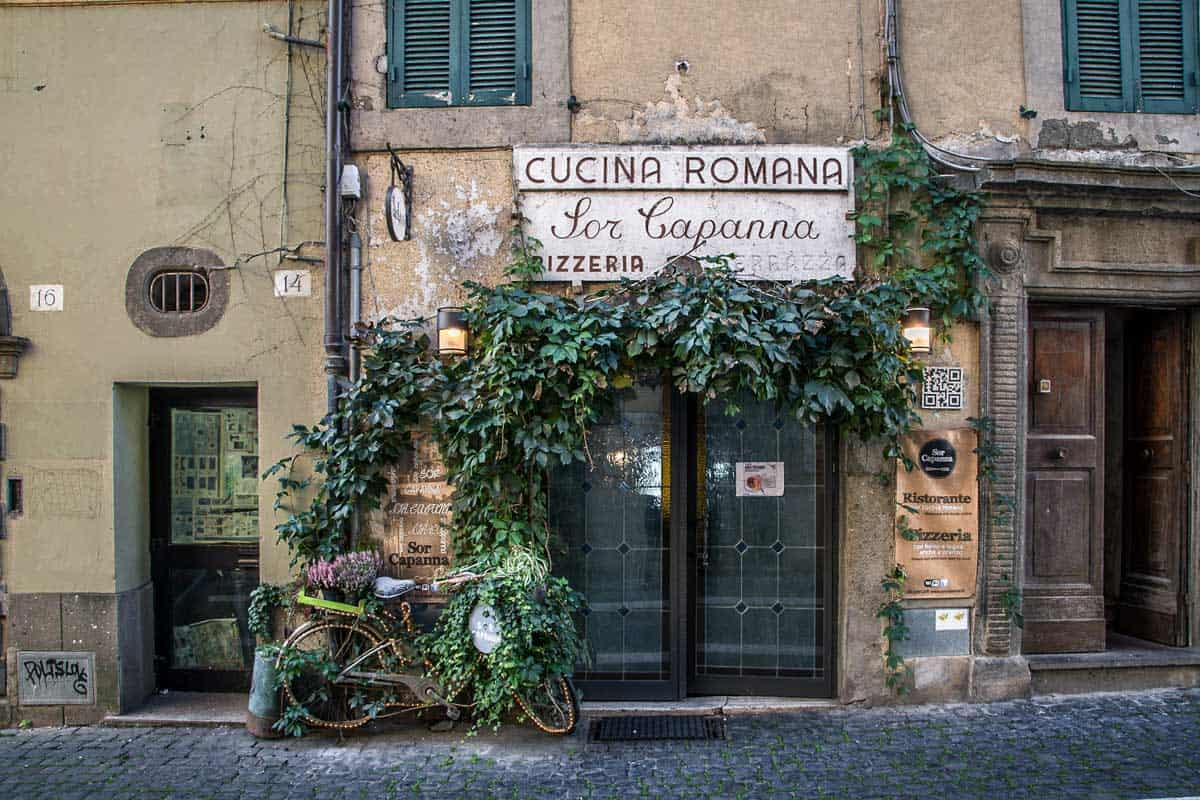 A tradiotnal pizzeria covered in vines with a bicicly out front in the small Italian town of Castel Gandolfo.