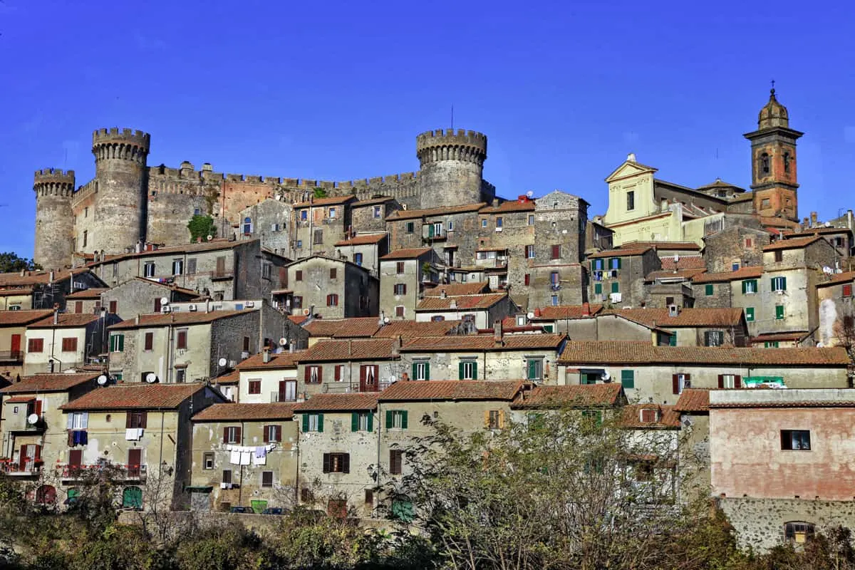 A castle rises above a stone village in Italy.