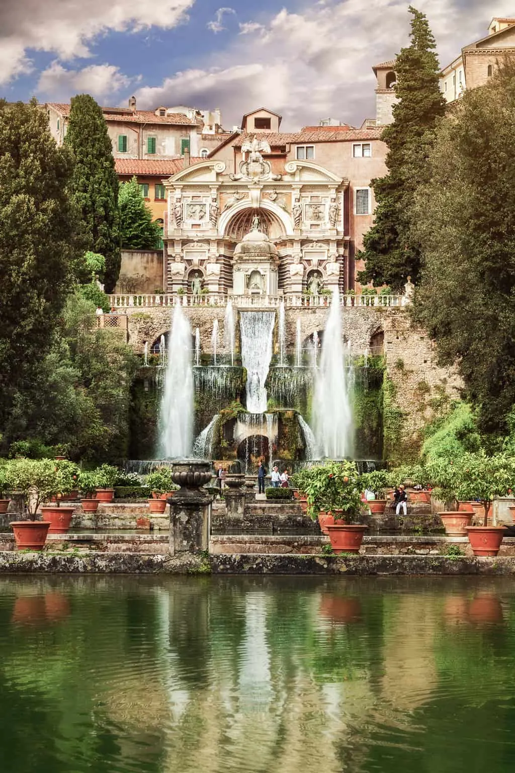 Ornate fountains in front of a large palace overlooking a lake in Italy.