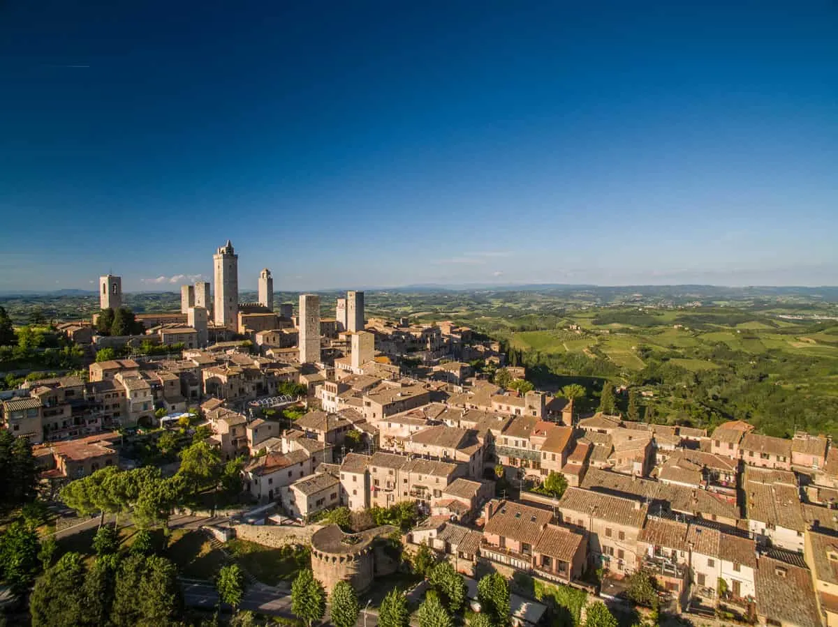 Aerial view of the medieval Italian town of Montepulciano surrounded by green countryside.