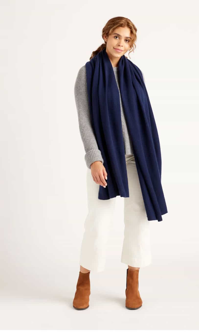 A young woman modelling a winter jeans and jumper outfit with an oversized blue scarf.