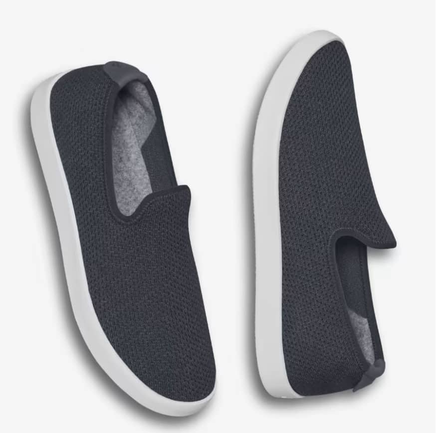A product shot of a pair of women's black slip on shoes with white soles.