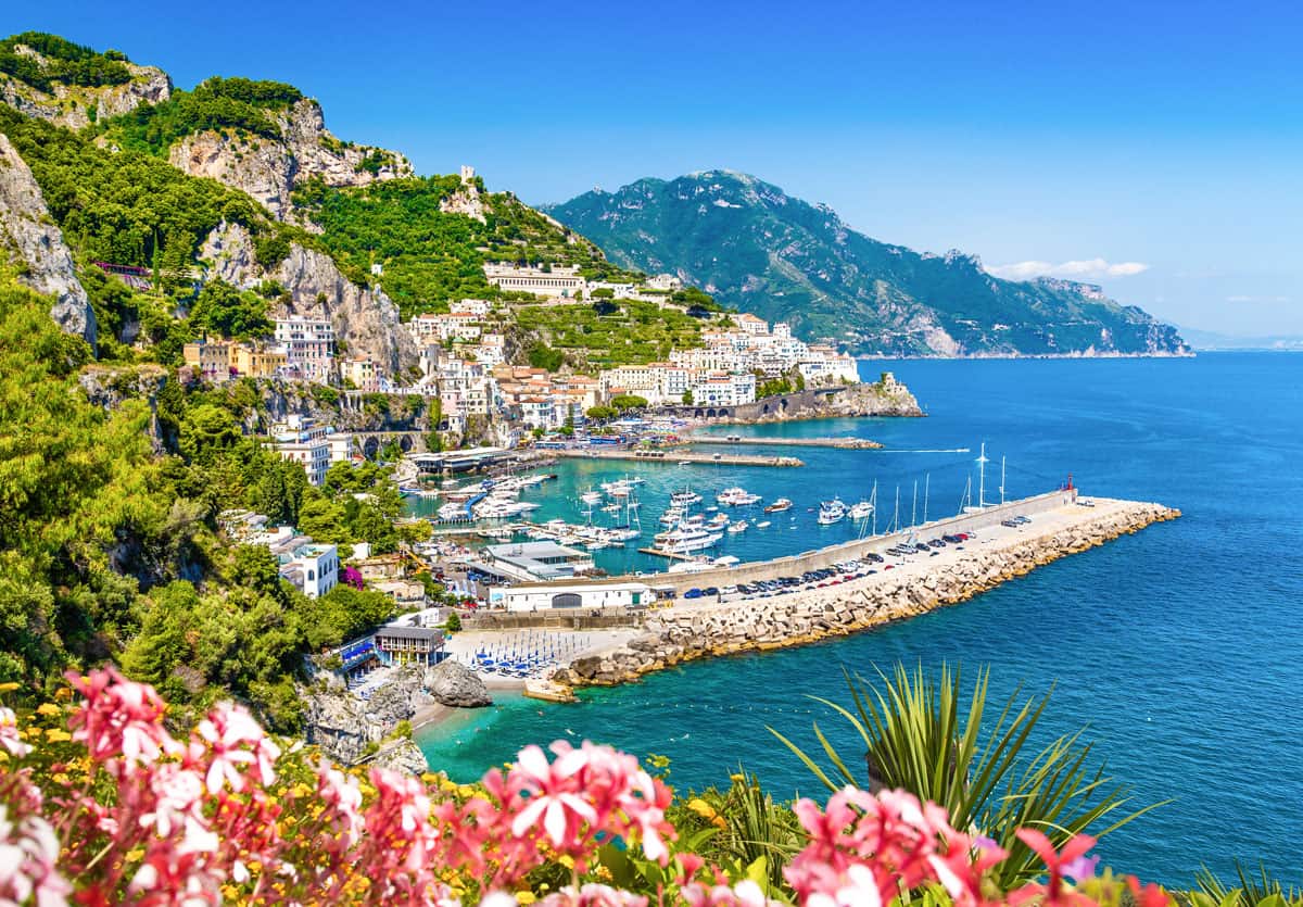Views from a scenic lookout over the marina and town of Amalfi on a sunny day with a vibrant turquoise sea.