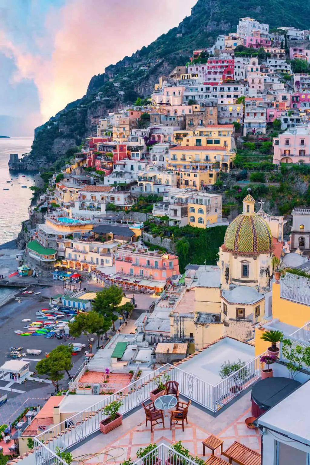 Pastel coloured building cascade down the hill at dusk in Positano on the Amalfi Coast.