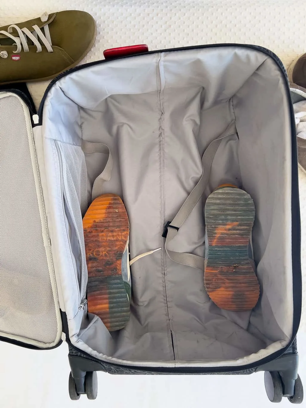 A pair of sneakers face down in an empty suitcase. 