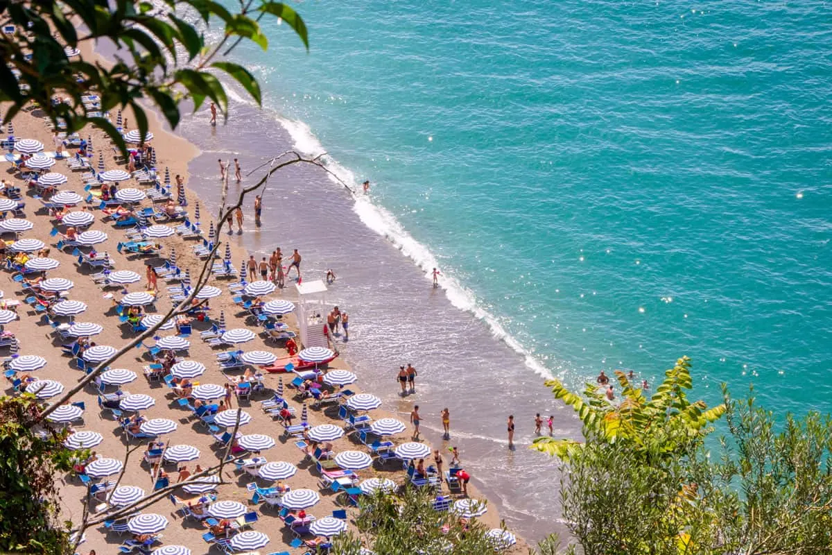 Blue and white umbrellas in neat rows along a pristine beach with clear blue water.