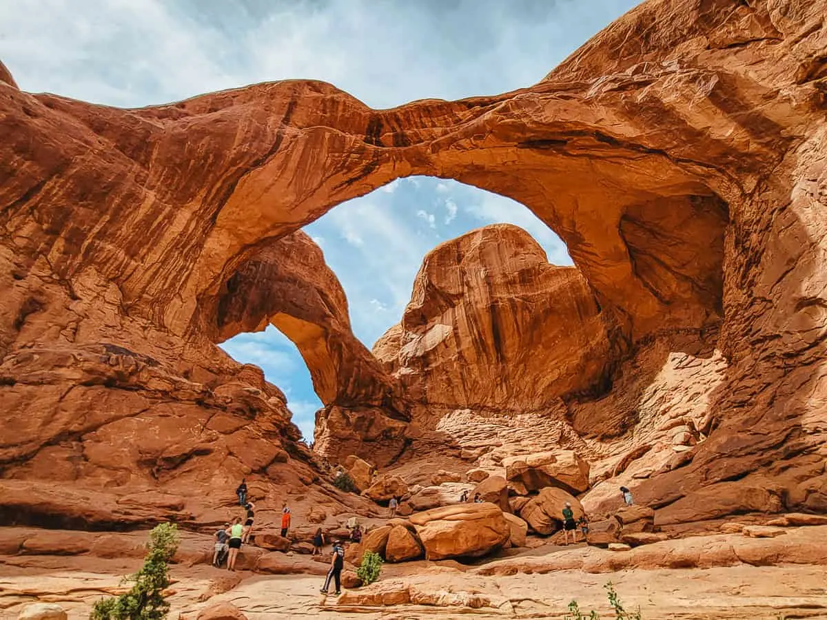 Hikers gathered under natural rock arches in Arches National Park. 