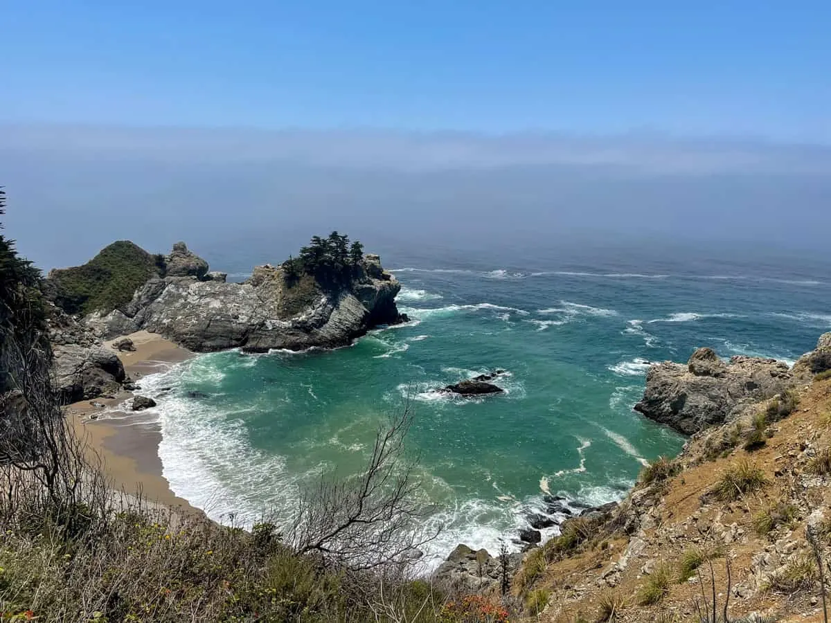 Views over the rocky coast line where it meets the blue sea on the Pacific Coast Highway. 