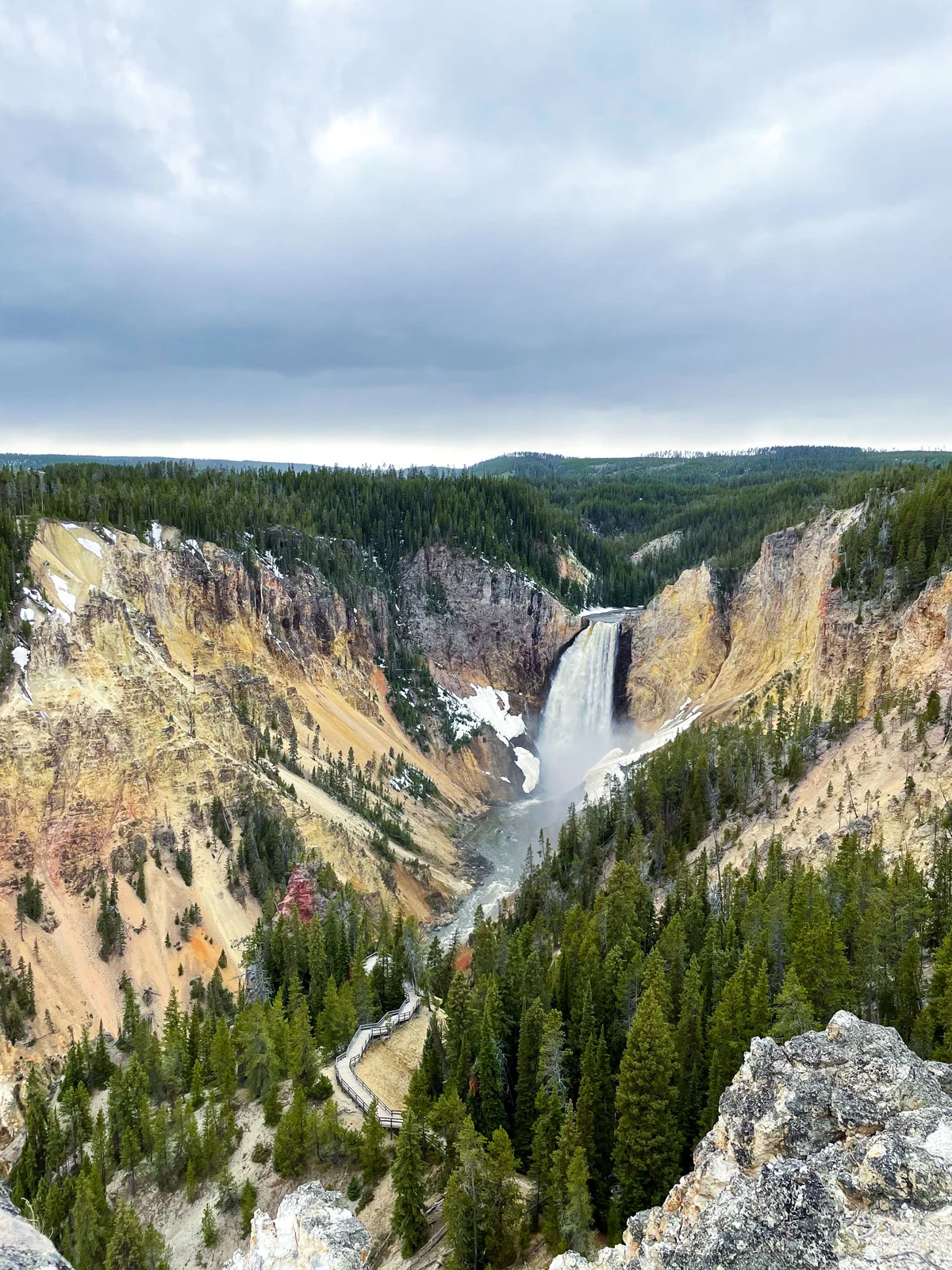 A rushing waterfall through the middle of a yellow rock canyon in Yellowstone NP.