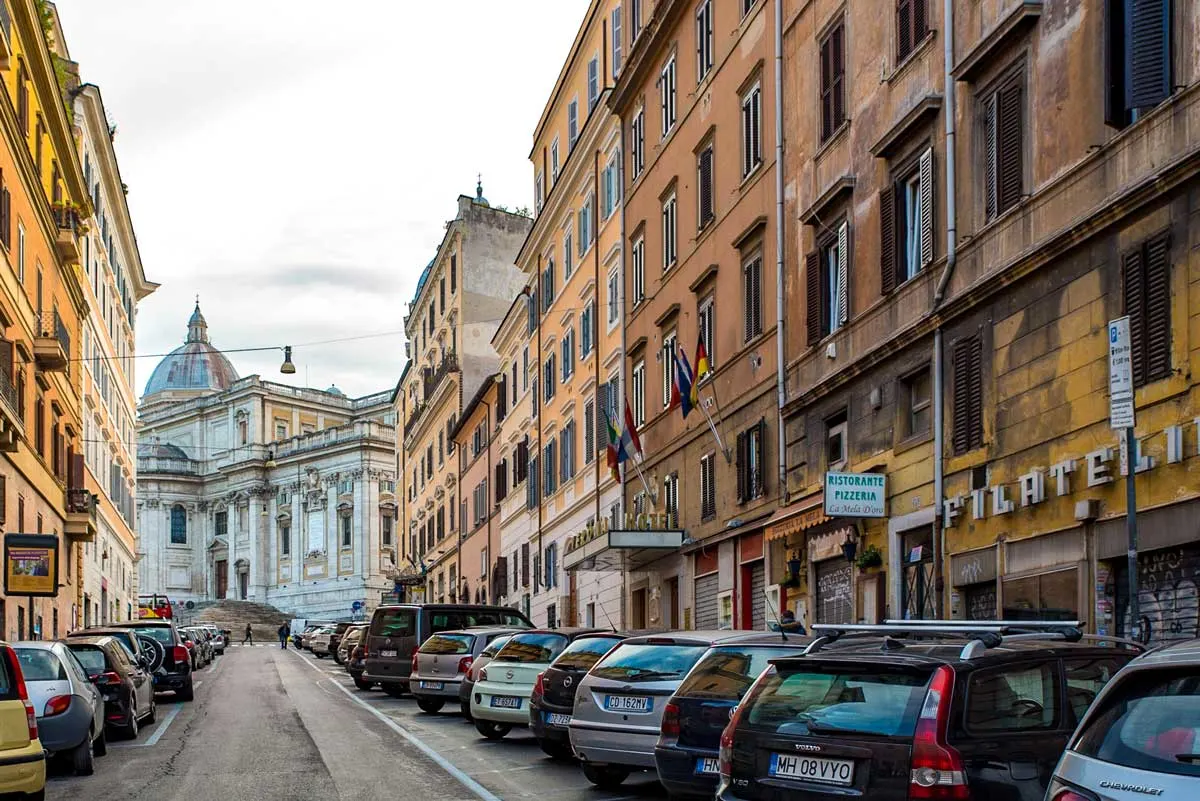 An inner city street in Esquilino Rome with a domed church at the end. 