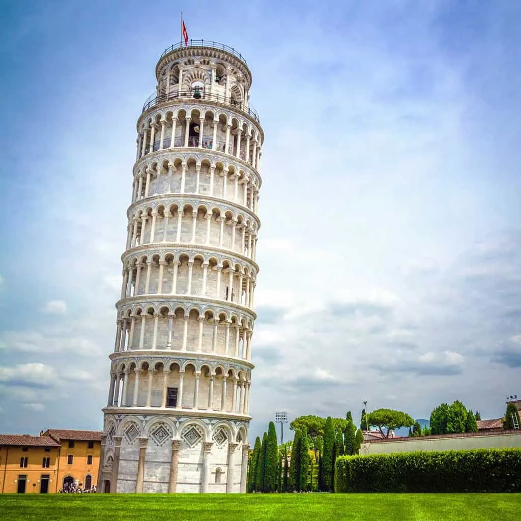 The leaning tower of Pisa on a sunny day with green grass in front. 